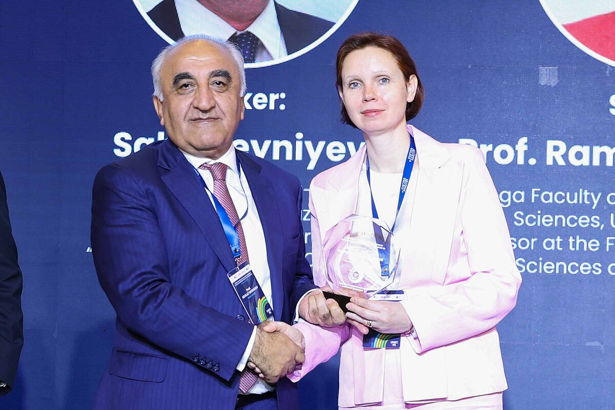 Prof. Rupeika Apoga saņem balvu par ieguldījumu pētniecībā un sabiedrības finanšu izglītībā. Konferences publicitātes foto.